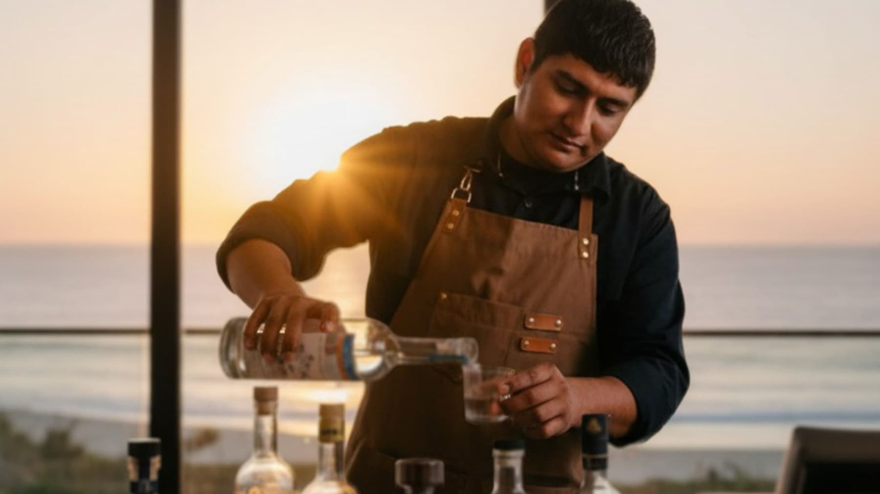 Sebastian pouring mezcal during an in-villa tasting at sunset